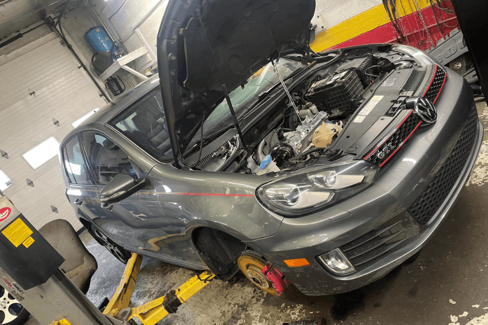 Car safety inspection, auto repair in Hanover, PA at Alex’s Autoworks. Image of a Volkswagen GTI on a lift with the hood open during engine service.