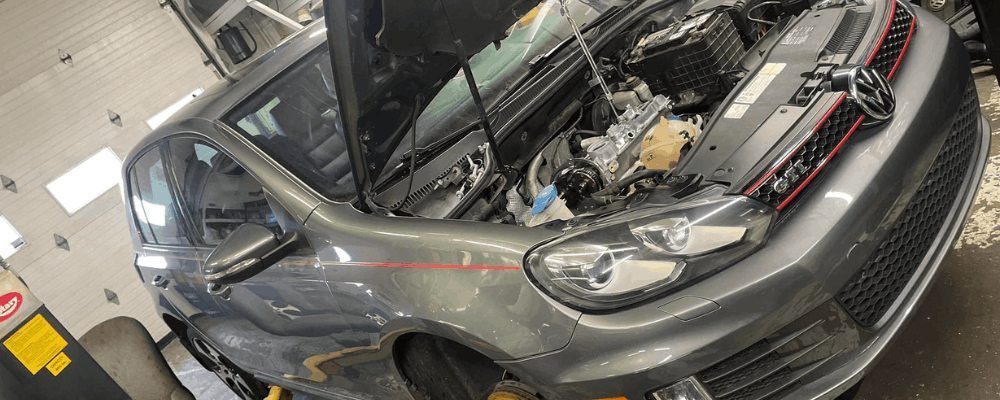 Car safety inspection, auto repair in Hanover, PA at Alex’s Autoworks. Image of a Volkswagen GTI on a lift with the hood open during engine service.