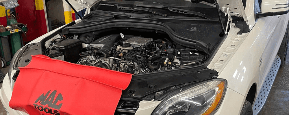 routine maintenance, auto repair in Hanover, PA at Alex's Autoworks. White Mercedes-Benz vehicle in a repair shop with its hood open, revealing the engine.